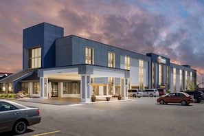 A modern hotel with a covered entrance, multiple parking spaces, and a clear sky. - Comfort Inn & Suites Evansville Airport (Evansville)