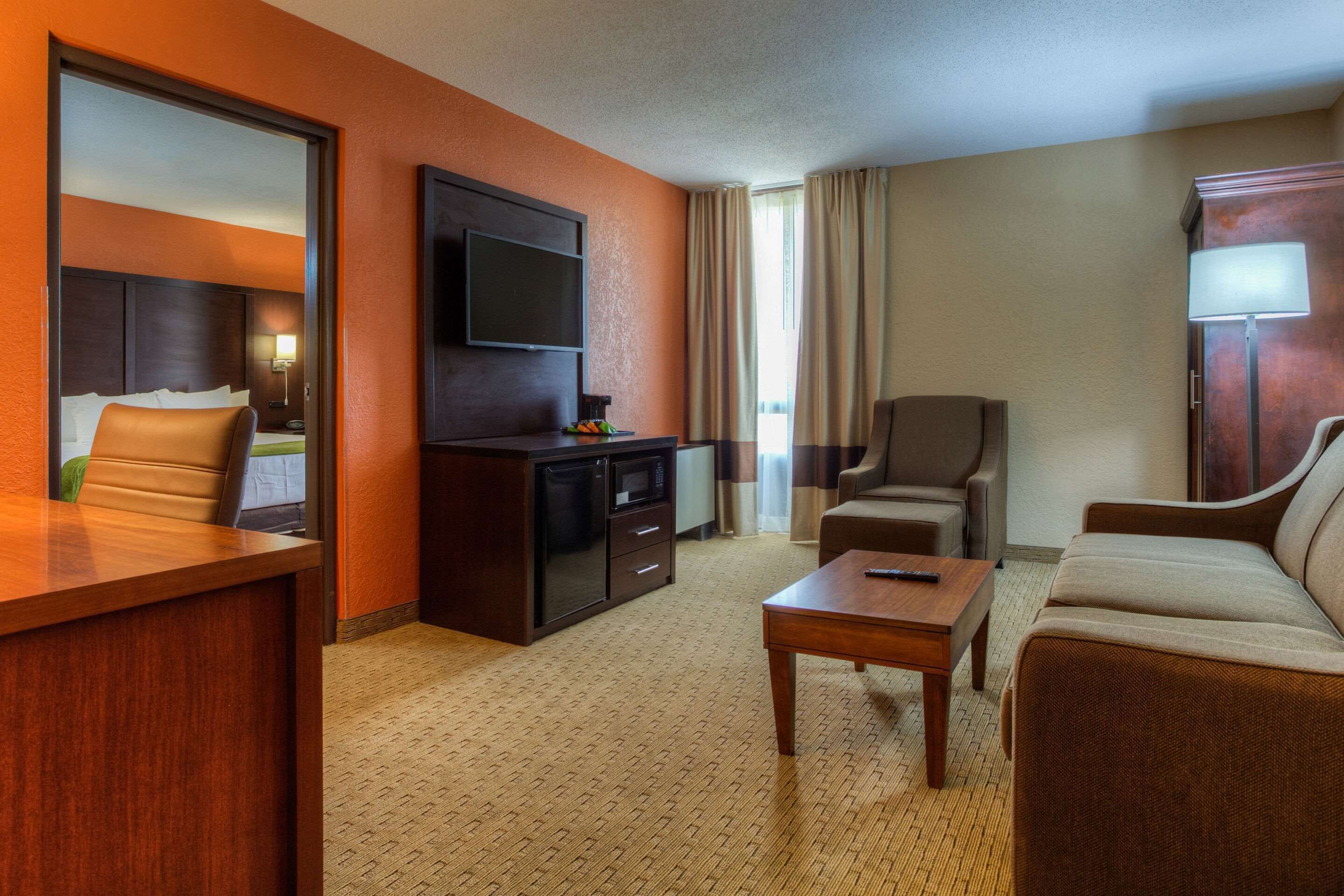 A hotel room with a bed, a desk, a TV, a sofa, and a coffee table.