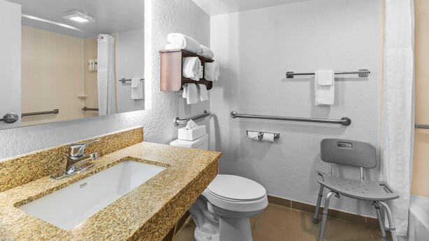 A modern bathroom with a granite countertop sink, a white toilet, a shower with a glass door, and a grab bar for safety. - Comfort Inn & Suites Evansville Airport (Evansville)
