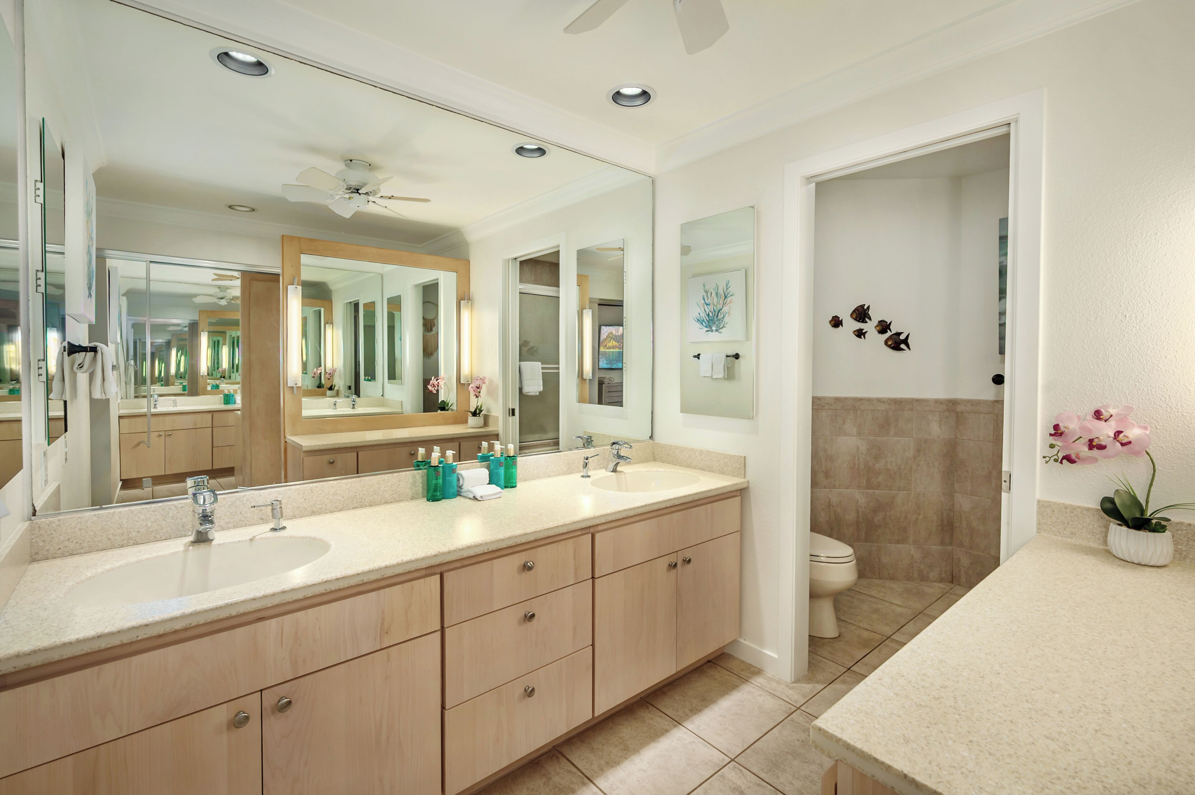 Un bagno moderno con doppio lavabo, un ampio specchio e una ventola a soffitto.