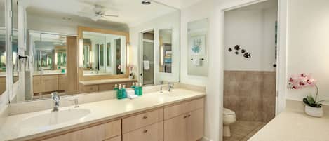 Un bagno moderno con doppio lavabo, un ampio specchio e una ventola a soffitto.
