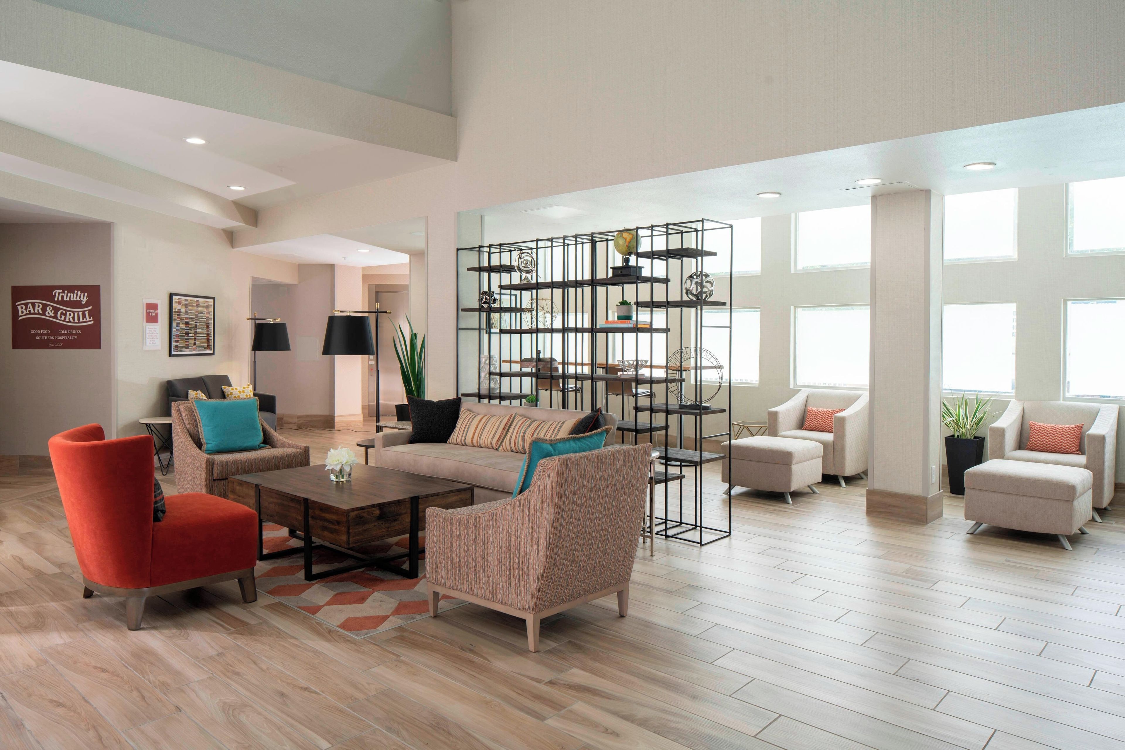 Un salón espacioso de diseño moderno, con un sillón rojo, un sofá color beige y una original estantería metálica.