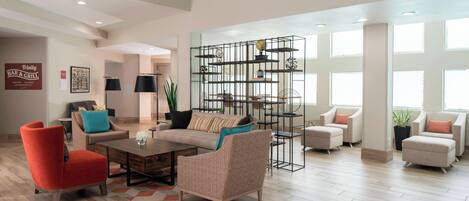 Un salón espacioso de diseño moderno, con un sillón rojo, un sofá color beige y una original estantería metálica.