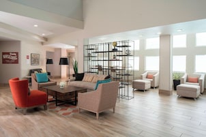 Un salón espacioso de diseño moderno, con un sillón rojo, un sofá color beige y una original estantería metálica.