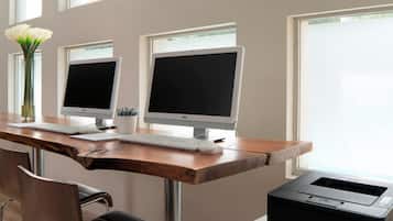 Ein Arbeitsplatz mit zwei Desktop-Computern, einer Tastatur, einer Maus, einer Vase mit Blumen und einem Brother-Drucker.