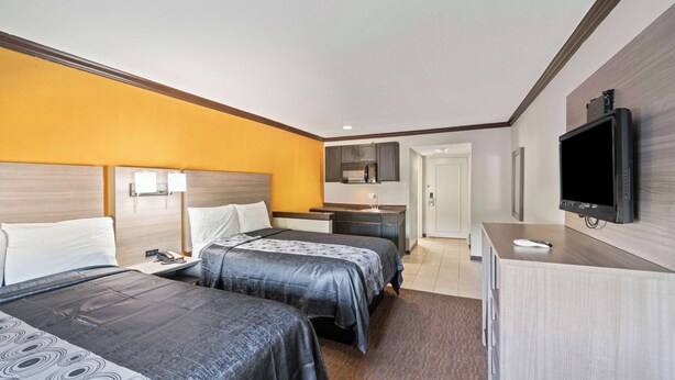 A hotel room with two beds, a desk, a television, and a bathroom visible through an open door.