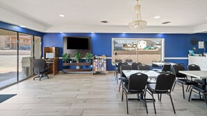 A modern dining area with a large window, a chandelier, and a flat-screen TV on the wall. - Americas Best Value Inn & Suites Brenham (Brenham)