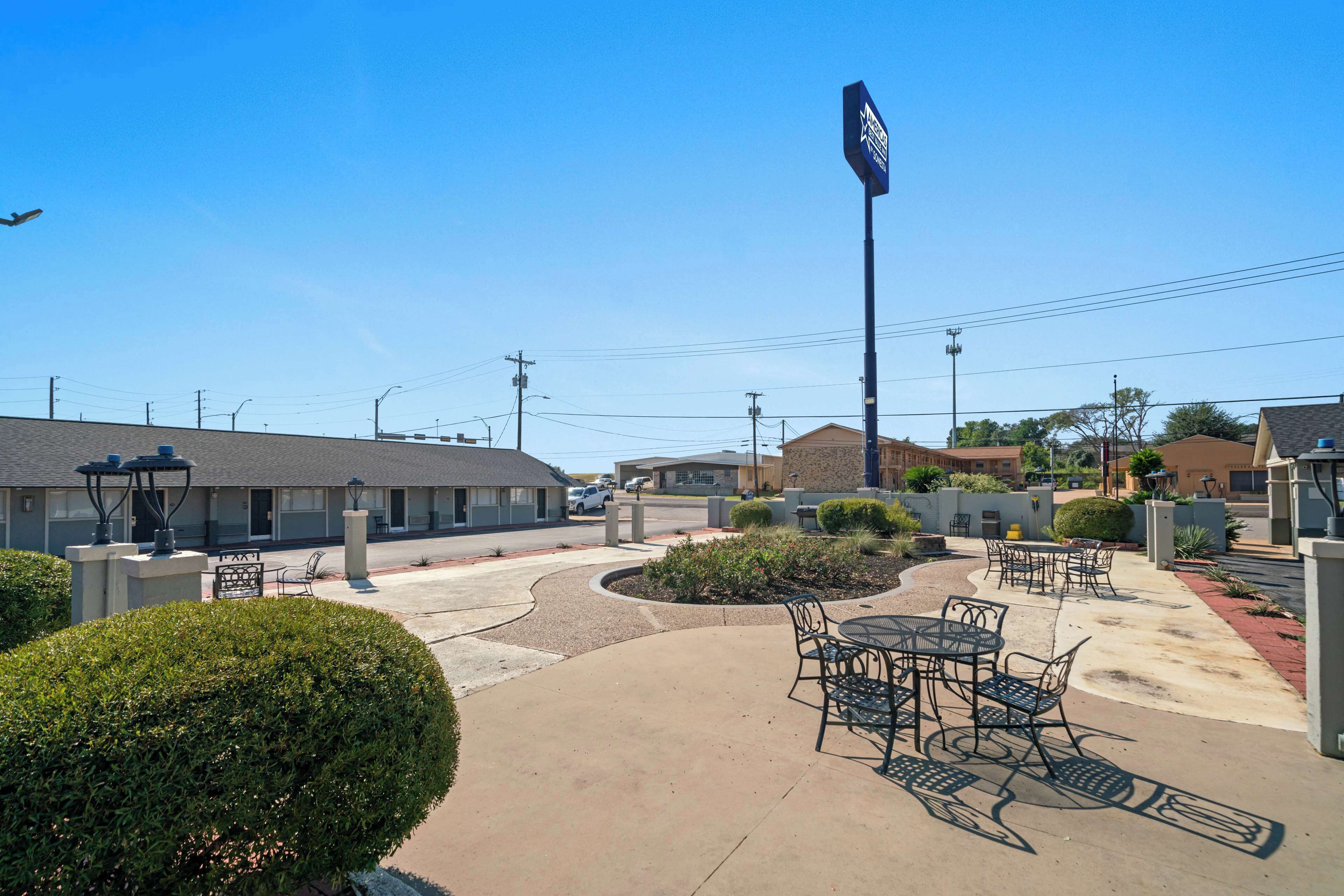 A hotel courtyard with outdoor seating, a large sign, and surrounding buildings.