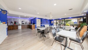 A modern restaurant with a blue and white color scheme, featuring a kitchen area, dining tables, and chairs. - Americas Best Value Inn & Suites Brenham (Brenham)