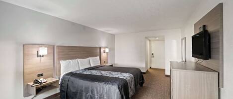 Een hotelkamer met een bed, nachtkastjes, een televisie en een vloerbedekking.