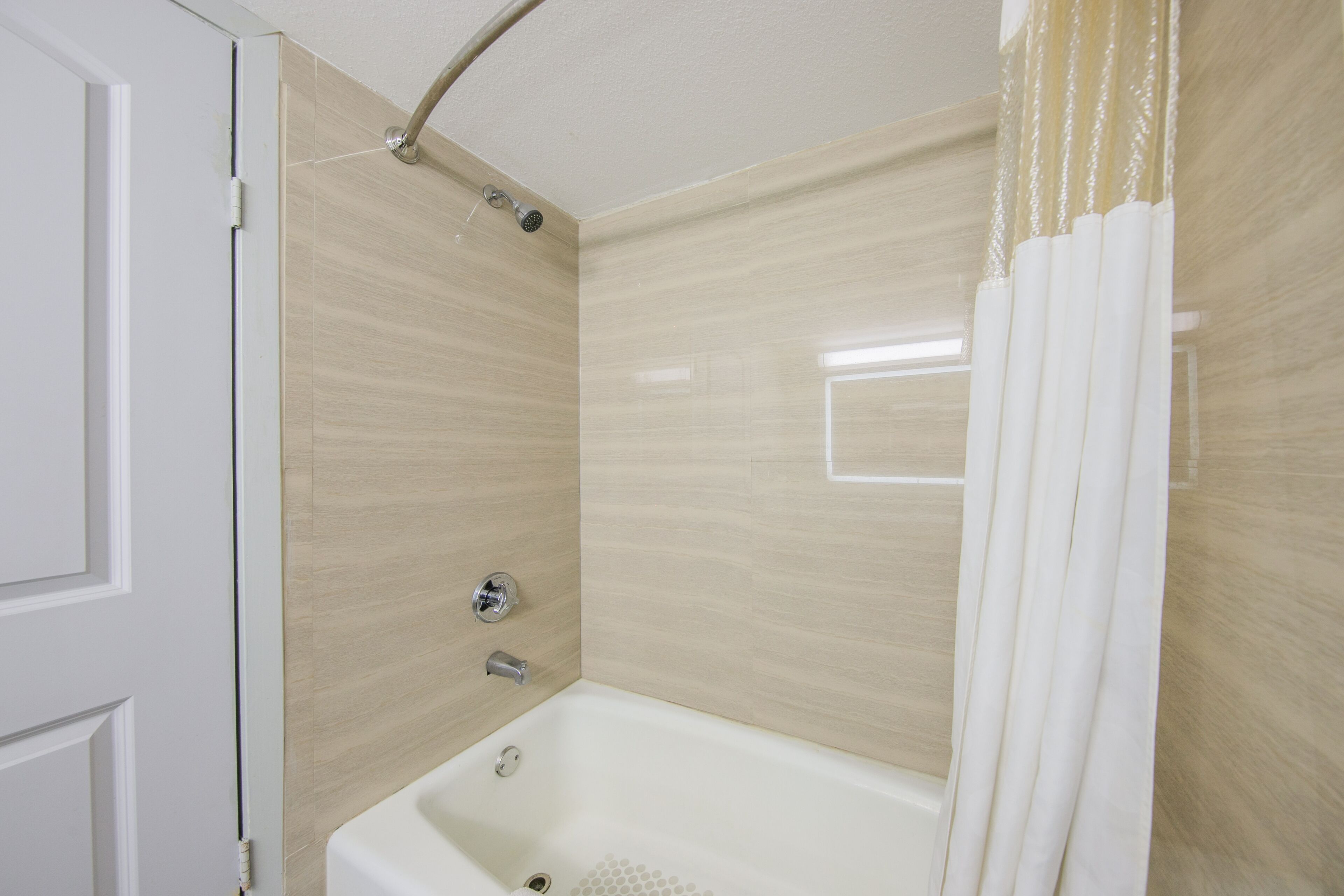 A bathroom with a bathtub, shower, and a door.