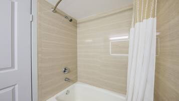 A bathroom with a bathtub, shower, and a door.