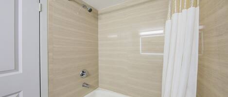A bathroom with a bathtub, shower, and a door.