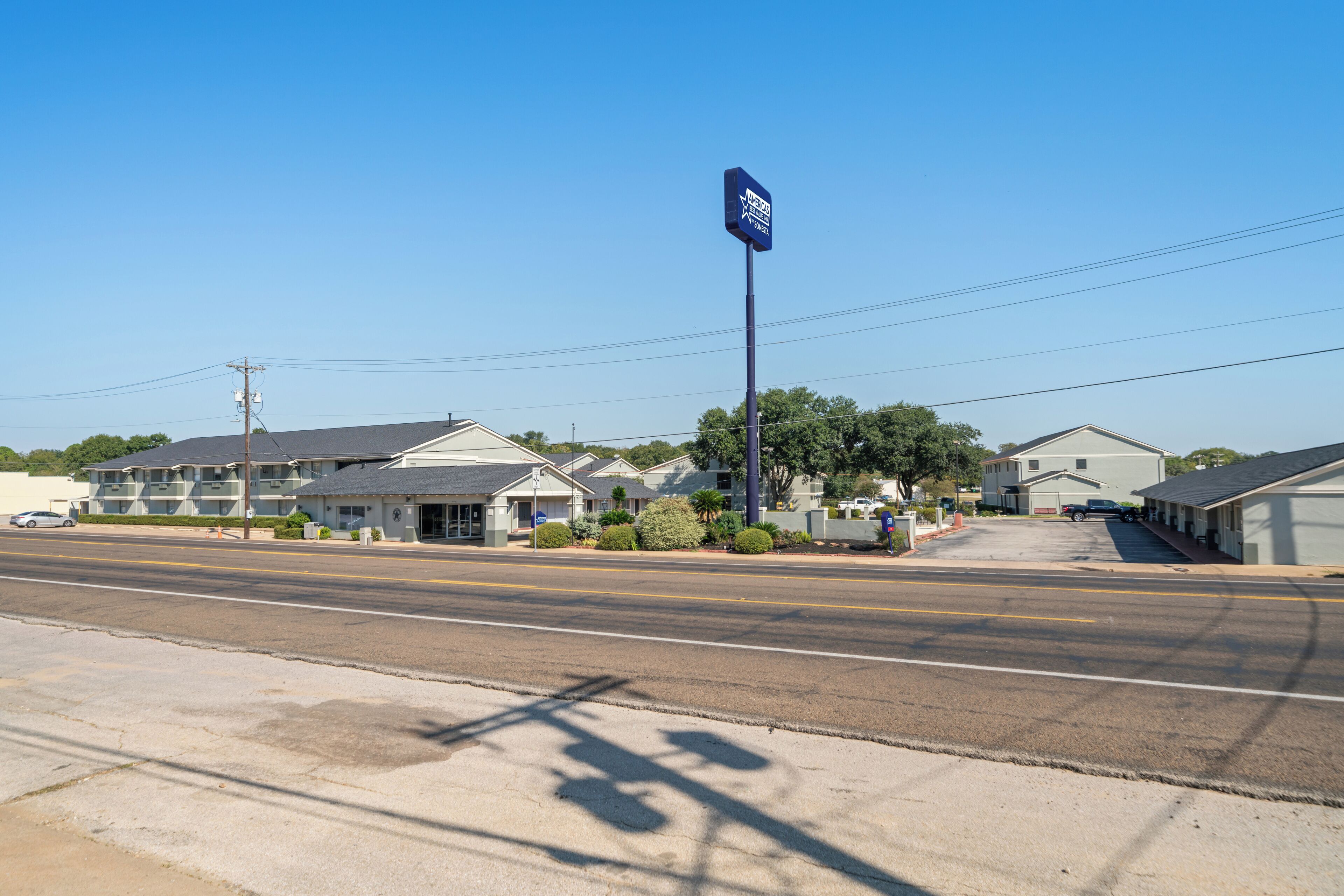 A motel with a blue sign, multiple-story buildings, and a clear sky.