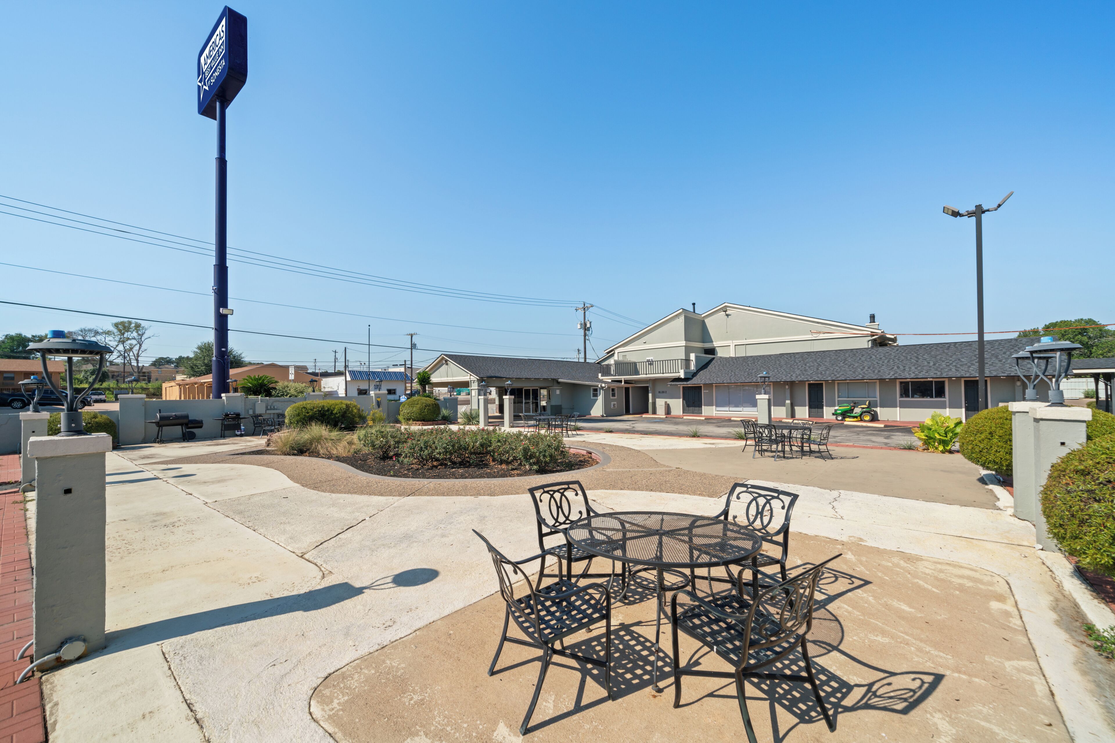 A hotel with outdoor seating, a clear sky, and a parking lot.