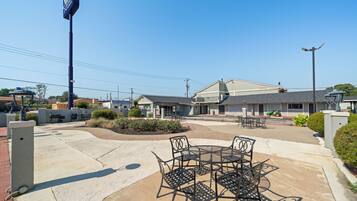 A hotel with outdoor seating, a clear sky, and a parking lot.