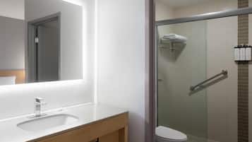 A bathroom with a mirror, sink, and shower.