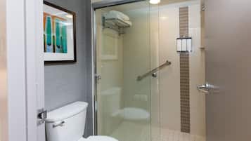 A modern bathroom with a glass-enclosed shower, a toilet, and a framed artwork on the wall.