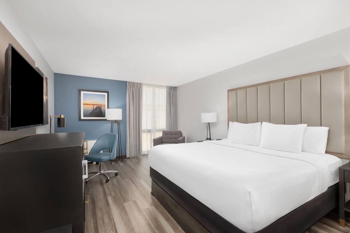 Hotelkamer met een groot bed, een bureau, een stoel, een televisie en een raam met gordijnen.