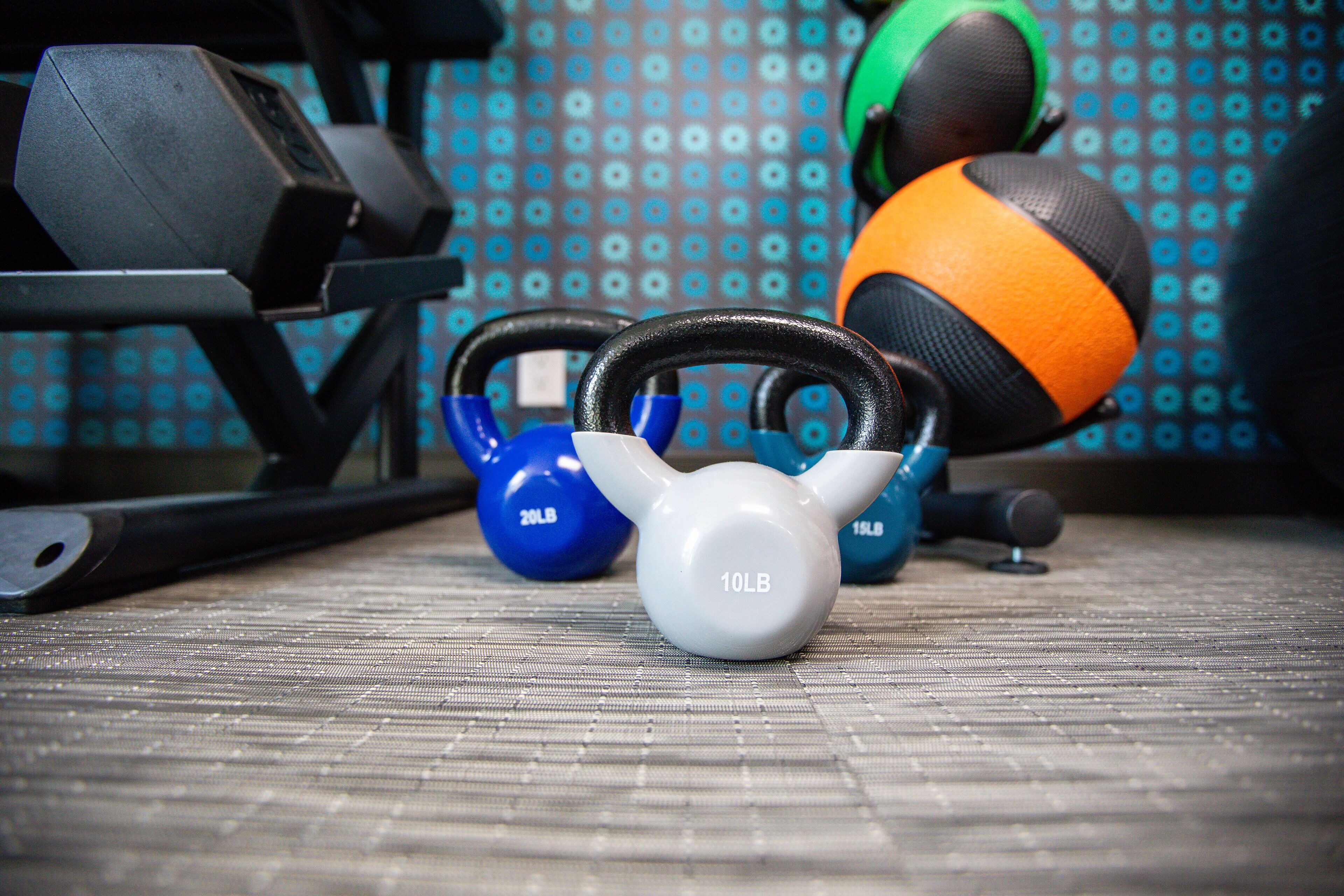 En kettlebell, hantlar och en medicinboll placerade på en yta med struktur.