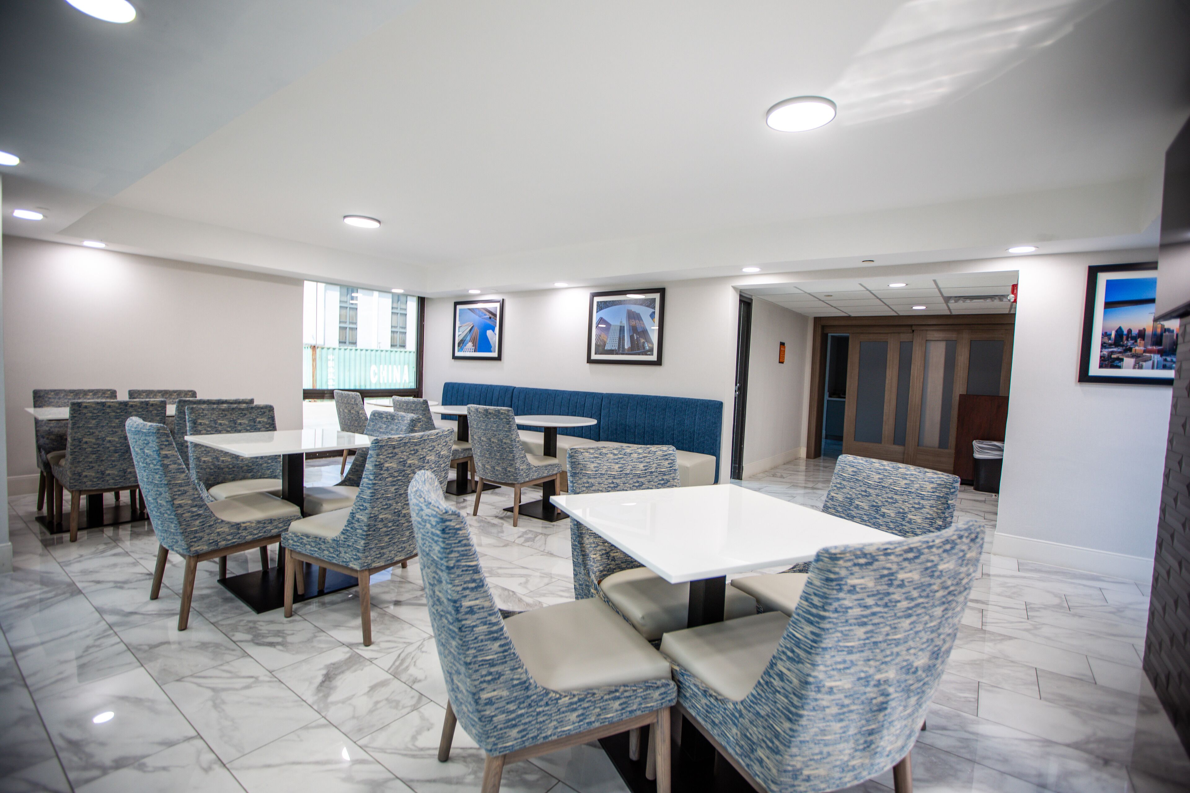 Een restaurant met marmeren vloeren, blauw gestreepte stoelen en witte tafels.