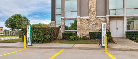 A building with two EV charging stations, a parking lot with yellow lines, and a stone facade.