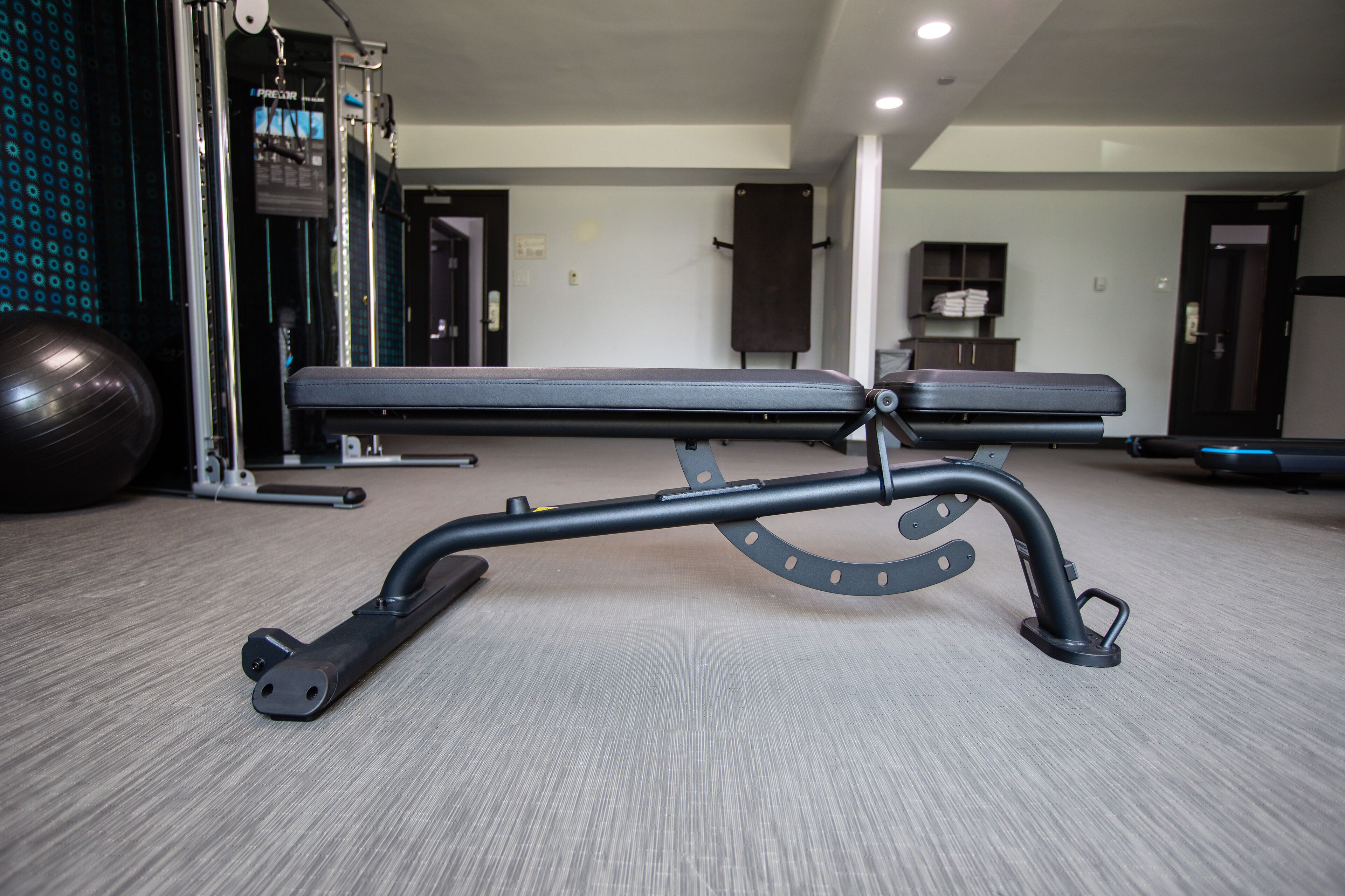A gym with exercise equipment, a bench, and a wall-mounted TV.