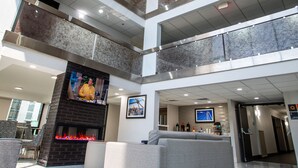 A multi-level atrium with a fireplace, seating area, and a television screen. - La Quinta Inn & Suites by Wyndham Dallas I-35 Walnut Hill Ln (Dallas)