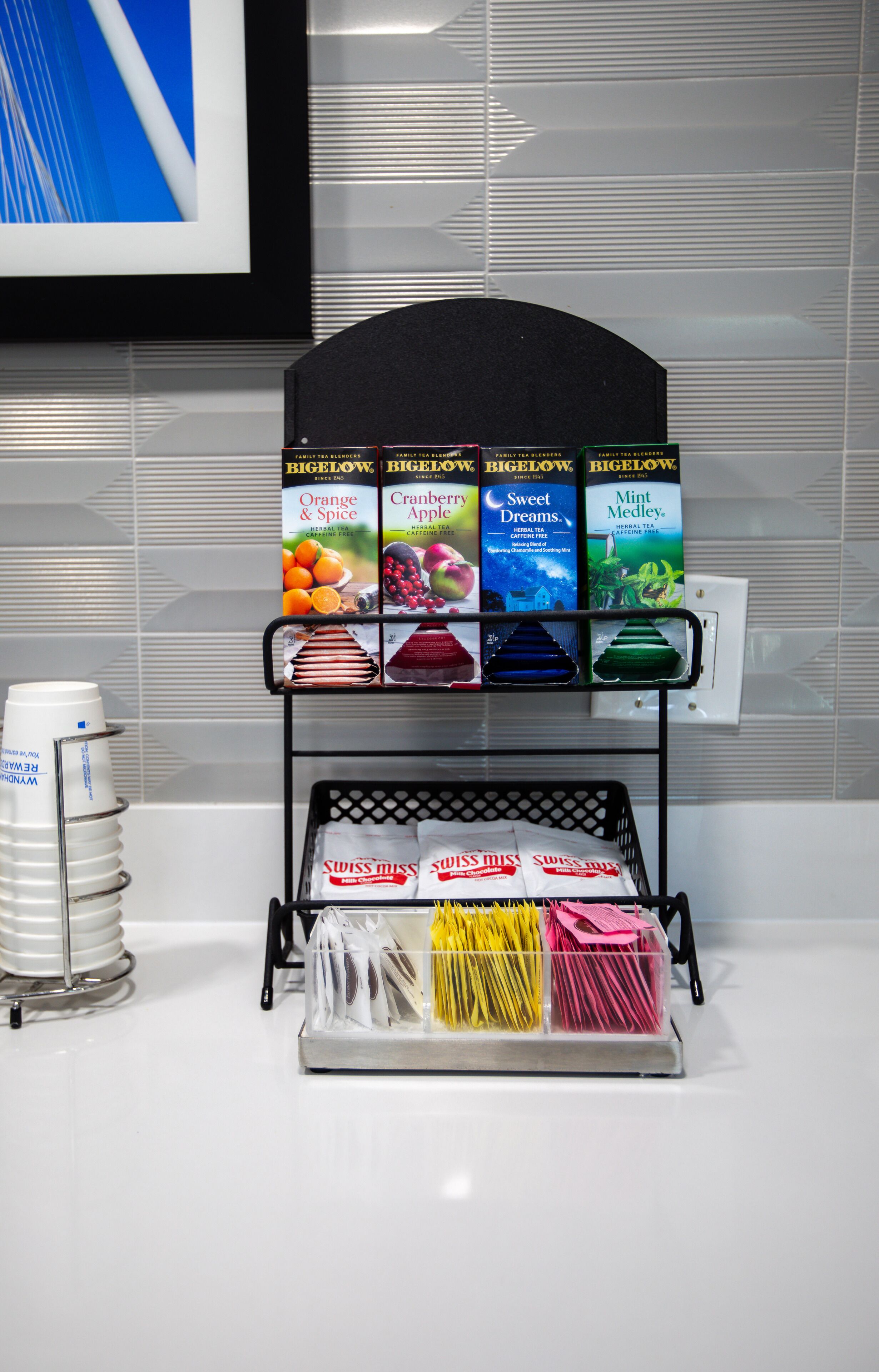 A coffee station with a selection of Bigelow tea bags and Swiss Miss tea bags.