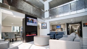 A spacious lobby with a fireplace, comfortable seating, a television, and a modern design. - La Quinta Inn & Suites by Wyndham Dallas I-35 Walnut Hill Ln (Dallas)