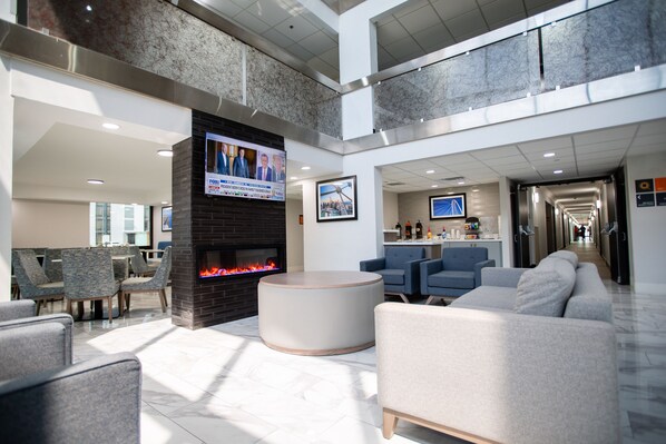 Un amplio vestíbulo con chimenea, asientos cómodos, televisor y diseño moderno.