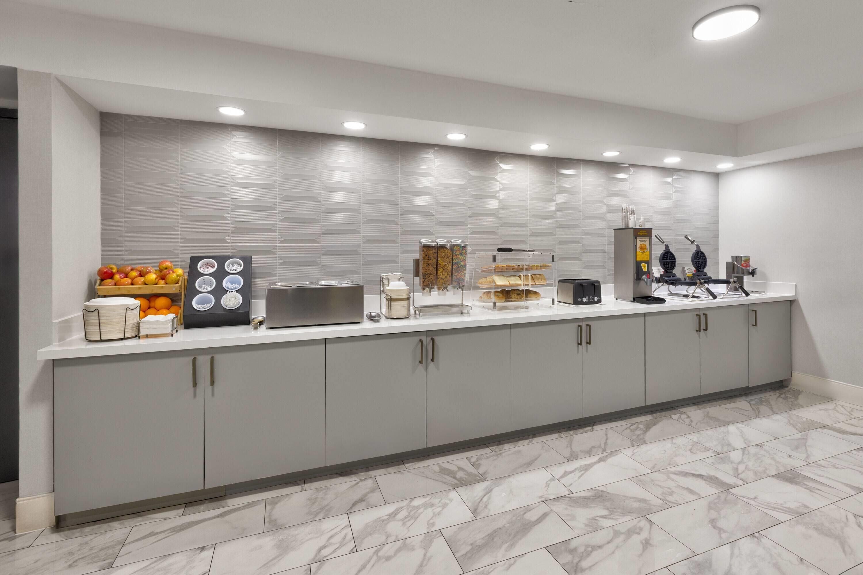 A modern kitchen with a marble floor, a breakfast bar, and various appliances.