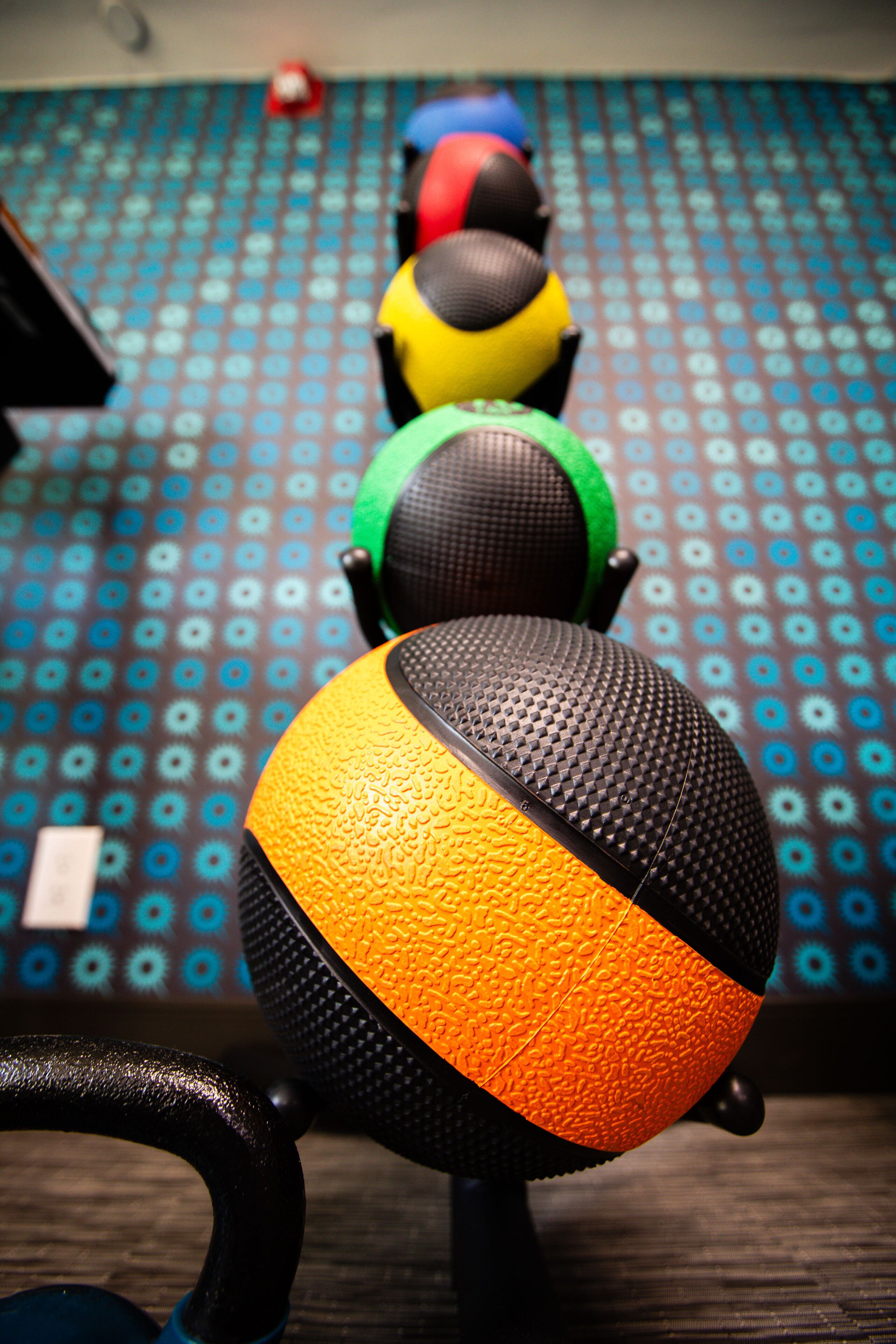 A row of exercise balls on a patterned floor.