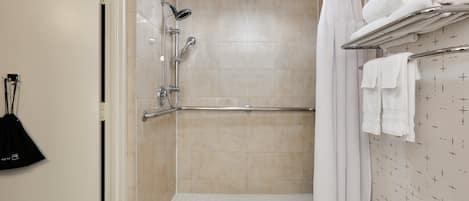 A walk-in shower with a grab bar, a towel rack, and a shower curtain.