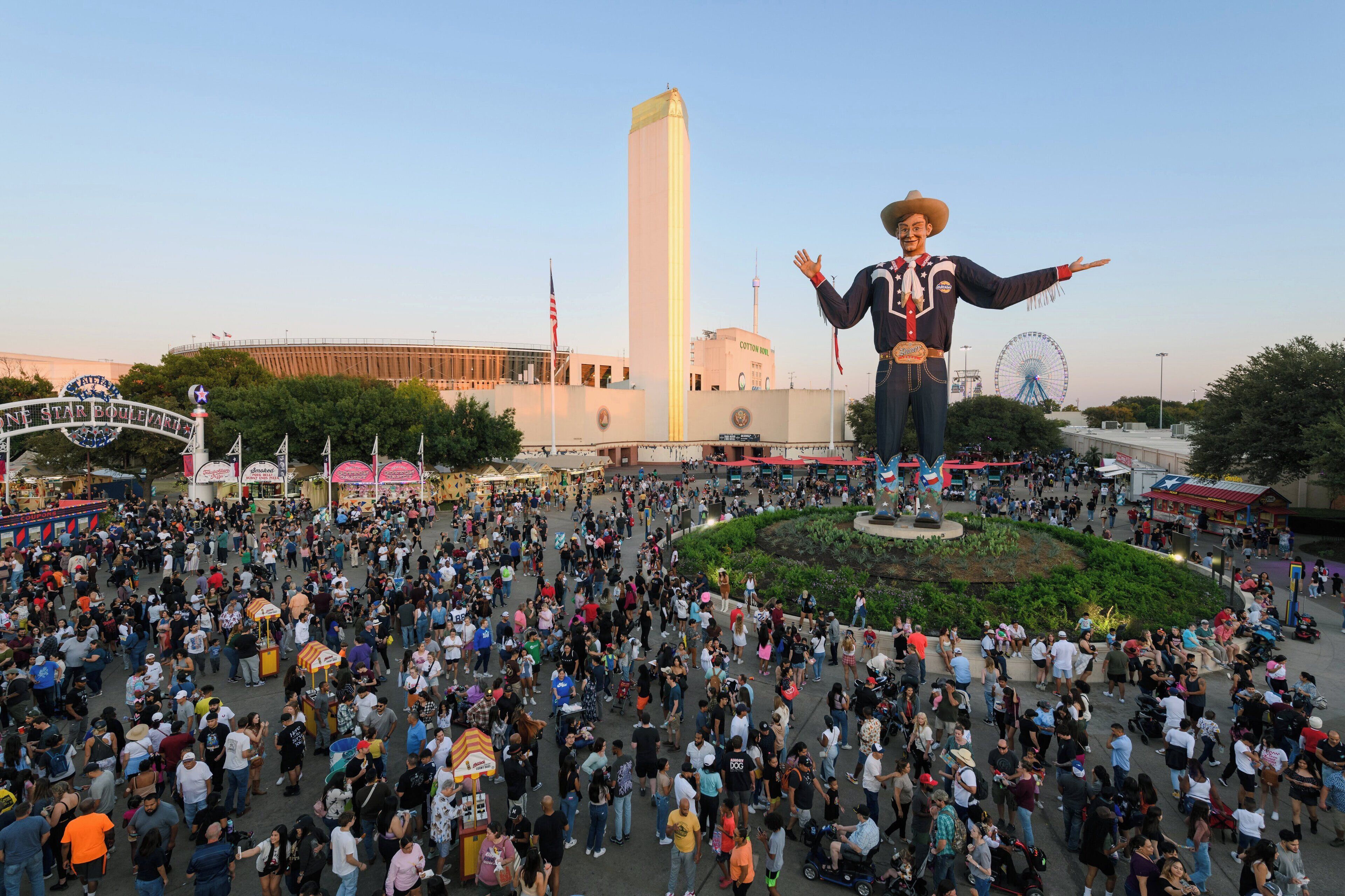 A large outdoor plaza with a central statue, surrounded by a crowd of people.