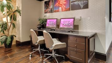 Un espacio de oficina moderno con un escritorio, dos sillas, dos monitores y una planta en maceta.