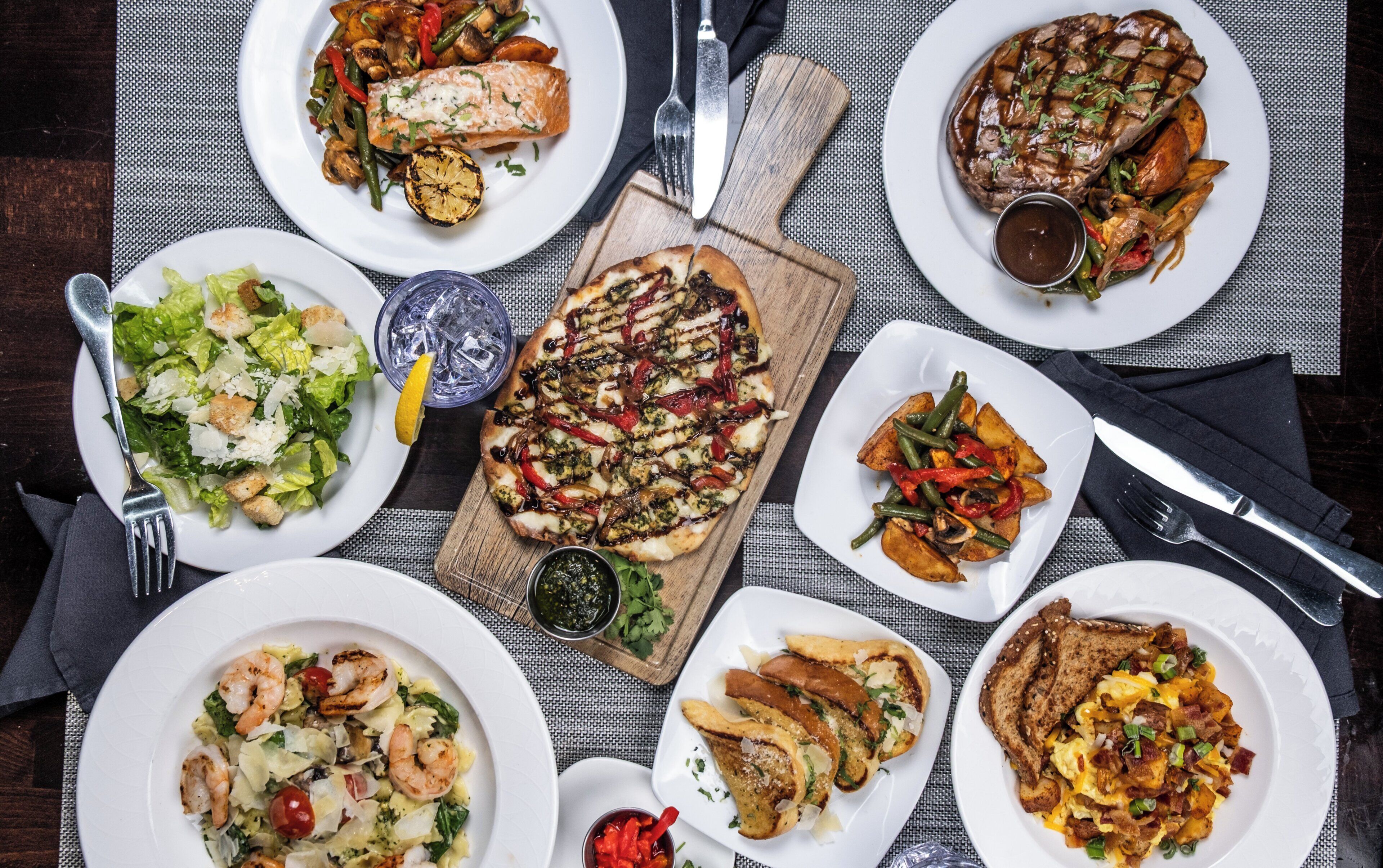 A variety of dishes on plates, including grilled salmon, steak, and vegetables.