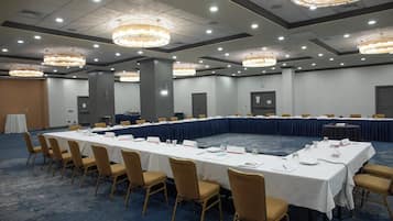 A conference room with a long table, chairs, nameplates, and a chandelier.