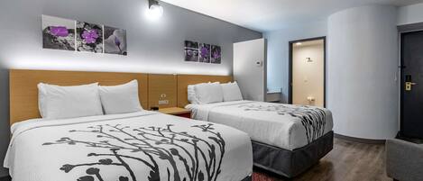 Habitación de hotel con dos camas, cabecero de madera, mesita de noche y alfombra roja.