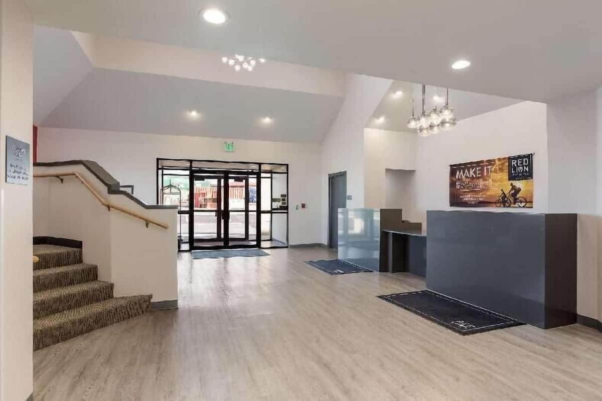 A modern reception area with a staircase, a glass door entrance, and a reception desk.