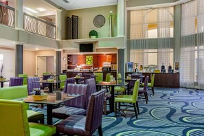 Guests can relax in the spacious lobby with a mezzanine level, featuring comfortable seating and a central counter for check-in and concierge services.