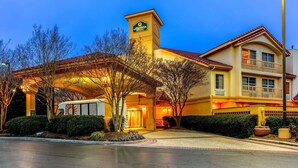 A hotel with a prominent sign, a covered entrance, and a well-maintained landscape.