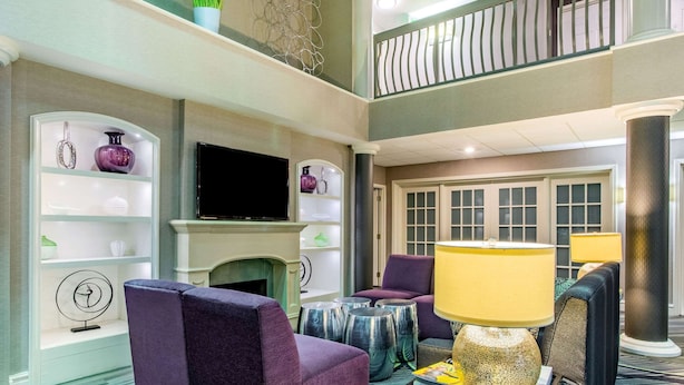 A modern hotel lobby with a fireplace, seating area, and a television.