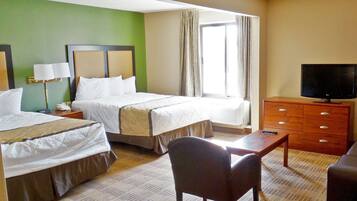 A hotel room with two beds, a television, a desk, and a chair.