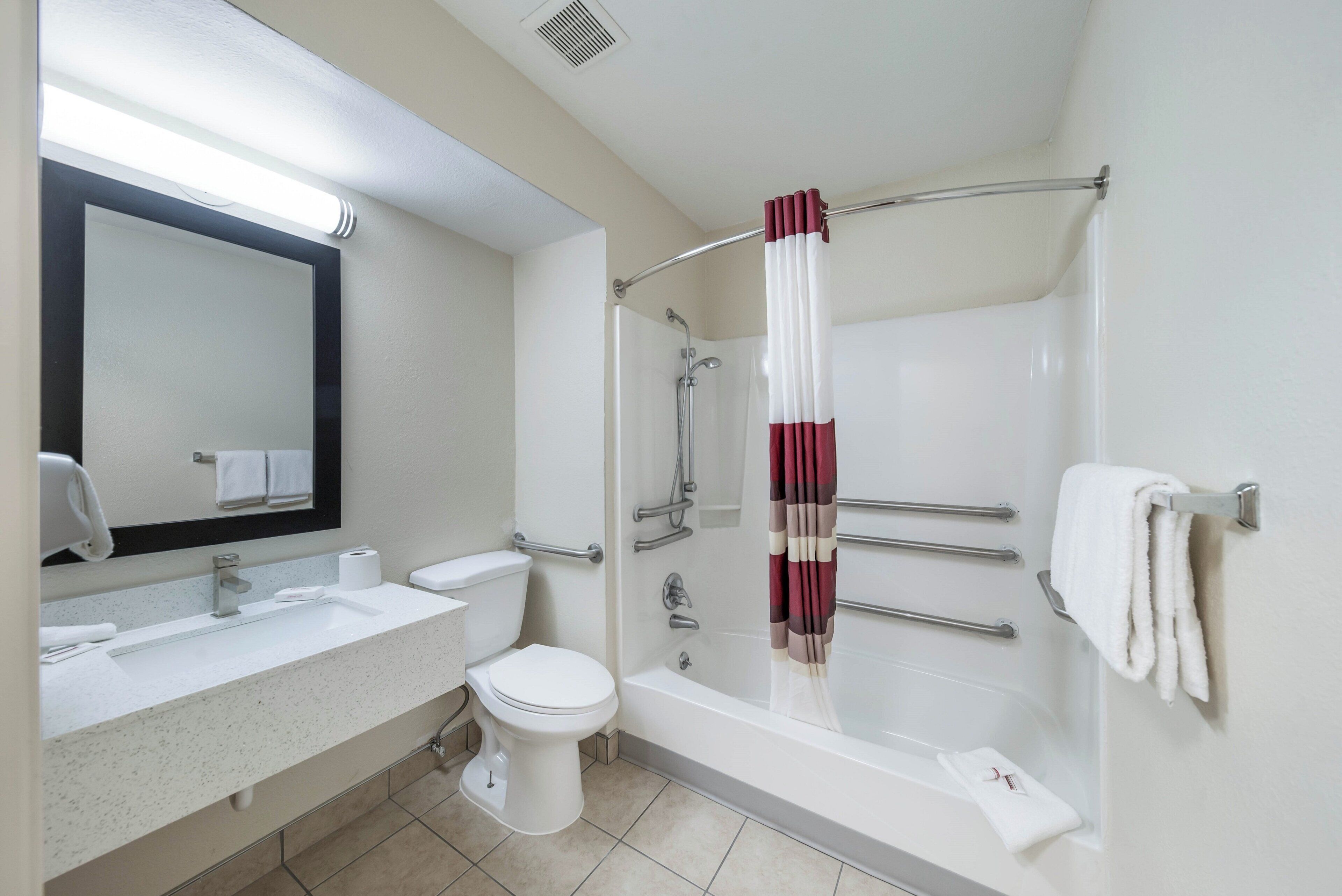 A bathroom with a bathtub, toilet, sink, and a mirror.