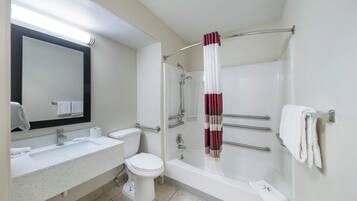 A bathroom with a bathtub, toilet, sink, and a mirror.