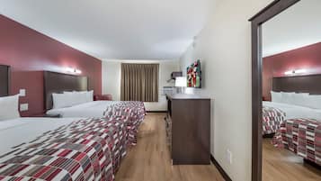 A hotel room with two beds, a desk, a mirror, and a TV.