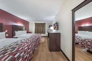 A hotel room with two beds, a desk, a mirror, and a TV. - Red Roof Inn & Suites Denton (Denton)