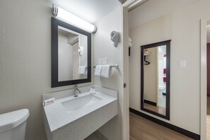 Sink, mirror, and towel rack in a bathroom with a wooden floor.