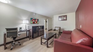 Uma sala de estar moderna com um sofá vermelho, uma mesa de centro, uma escrivaninha com abajur e uma televisão.